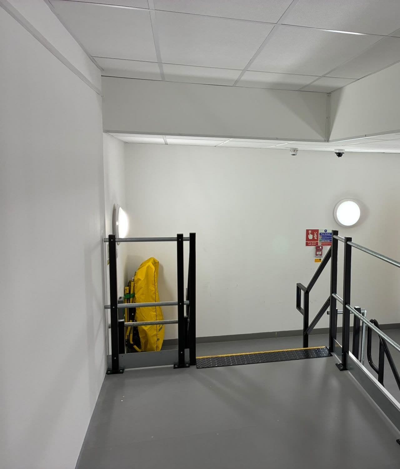 Top of the stairwell with white walls and a white boxed bulkhead below the ceiling