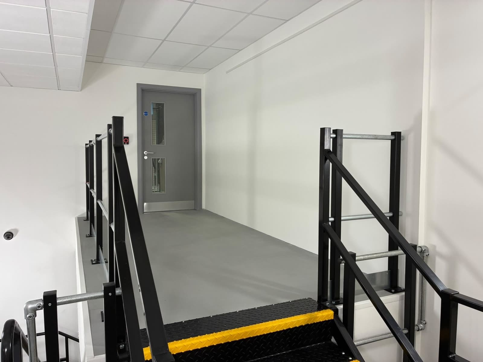 Grey door frame at the top of a stair, with white walls on both sides