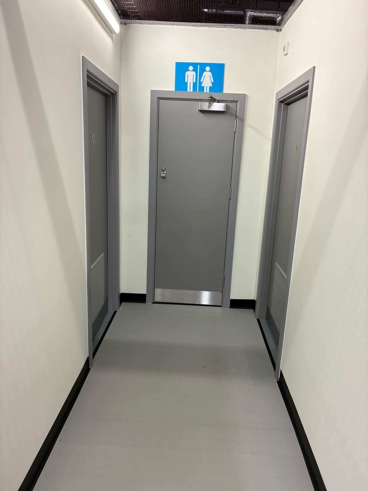Toilet corridor with white walls and grey door frames around three doors